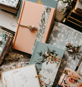 A collection of wedding planner books arranged on a table, each with unique covers, surrounded by wedding-themed stationery like invitations and a calendar.