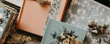 A collection of wedding planner books arranged on a table, each with unique covers, surrounded by wedding-themed stationery like invitations and a calendar.