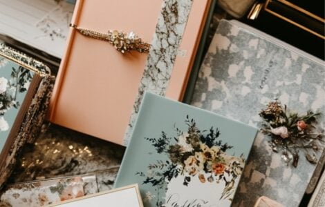A collection of wedding planner books arranged on a table, each with unique covers, surrounded by wedding-themed stationery like invitations and a calendar.