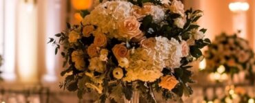 Wedding reception setup with elegant tables, floral centerpieces, and soft lighting in a grand venue.