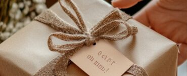 Close-up of hands exchanging a beautifully wrapped gift with a ‘Congrats on the engagement!’ tag, symbolizing thoughtful celebration of a couple's milestone.