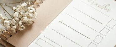 An elegant wedding budgeting guide displayed on a notepad with a calculator, pen, and wedding-themed decorations.