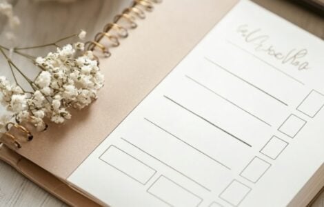 An elegant wedding budgeting guide displayed on a notepad with a calculator, pen, and wedding-themed decorations.