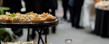 An elegant cocktail hour setup with small hors d’oeuvres being passed around and guests mingling in a beautifully decorated venue.