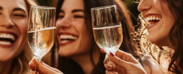 A group of women laughing and toasting with champagne glasses at a festive bachelorette party.