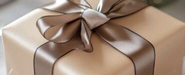 A beautifully wrapped gift box with a satin ribbon, placed on a bridal-themed table setting.