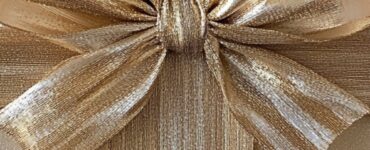 A beautifully wrapped golden gift box with a shimmering bow, symbolizing a milestone 50th wedding anniversary celebration.