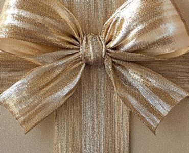 A beautifully wrapped golden gift box with a shimmering bow, symbolizing a milestone 50th wedding anniversary celebration.