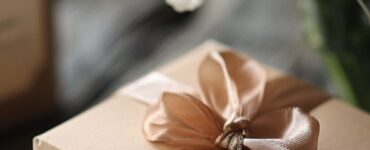 A beautifully wrapped gift box with a ribbon, placed on a table alongside a handwritten anniversary card.