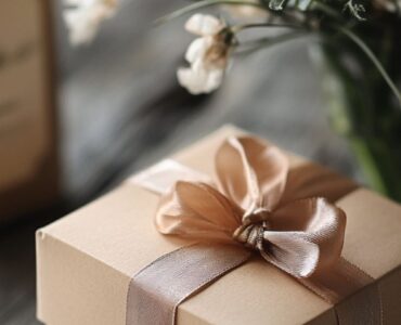 A beautifully wrapped gift box with a ribbon, placed on a table alongside a handwritten anniversary card.