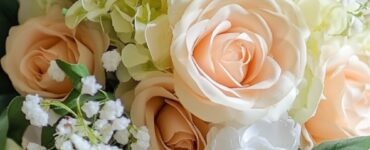 A photo of a beautifully arranged wedding bouquet made from artificial flowers, including roses, hydrangeas, and baby’s breath, resting on a white lace cloth.