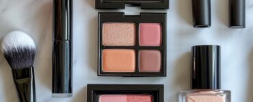 Flat lay of makeup products and brushes on a marble surface, including a foundation, eyeshadow palette, lipstick, and blush, representing a variety of bridal makeup styles.