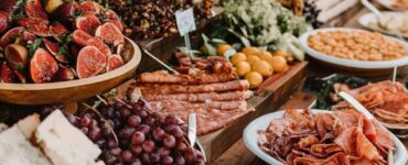 A beautifully arranged grazing table at a wedding, featuring a variety of food options that allow guests to serve themselves while adding to the event’s decor.