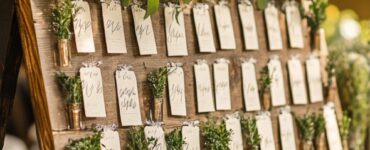 Wedding reception seating chart decorated with rustic and modern elements, featuring various creative designs such as calligraphy signs and greenery accents.