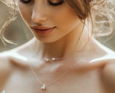 A bride wearing an elegant off-the-shoulder wedding dress, highlighting her neckline and shoulders with delicate lace detailing.