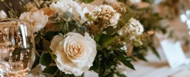 A beautifully decorated wedding table at a rehearsal dinner, featuring an elegant table runner, fine tableware, and a romantic ambiance.