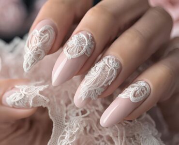 Close-up of nails with a soft pink base and intricate white lace overlay, exuding elegance and femininity reminiscent of delicate bridal lace.