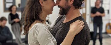 Couple learning dance steps together in a dance studio.