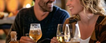 A happy couple enjoying a tasting session at a local winery, sampling different wines and craft beers, accompanied by a selection of cheeses and snacks.