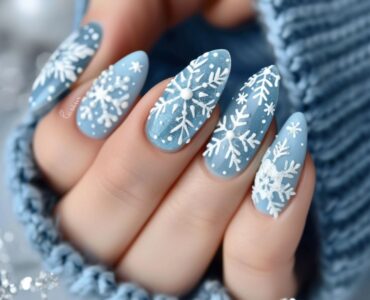 Close-up of nails adorned with delicate white snowflakes against a soft, icy blue backdrop, capturing the essence of winter with intricate details and subtle shimmer.
