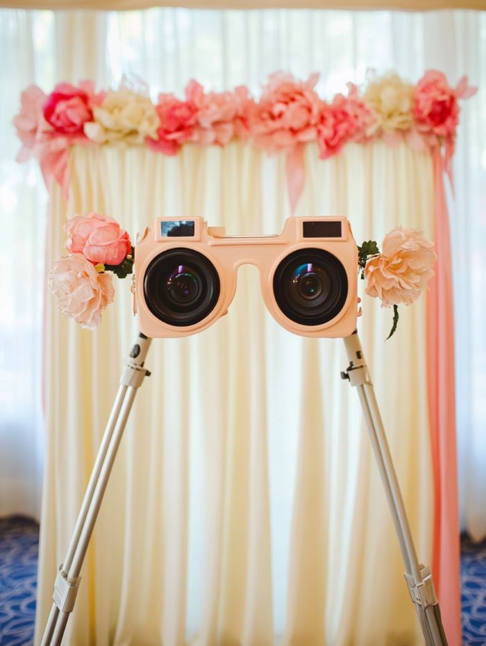A DIY photo booth at a wedding with fun props, a simple backdrop, and a camera for guests to take memorable photos.