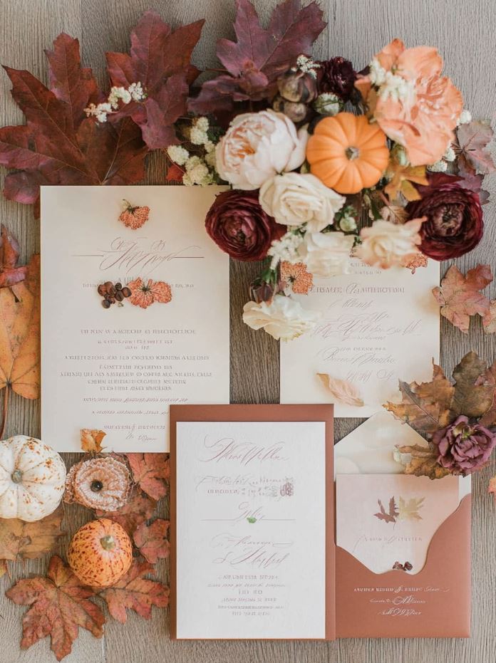 Autumn-inspired wedding invitations featuring fall motifs like leaves, pumpkins, and acorns, with rich color schemes and rustic fonts to reflect the cozy, seasonal theme.