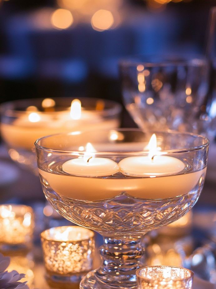 Elegant floating candles placed in crystal glass bowls, reflecting light for a sophisticated and luxurious wedding centerpiece.
