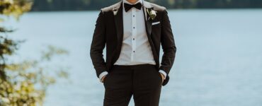 A groom standing confidently by the lake, dressed in attire that reflects his personal style, whether it's a formal tuxedo, casual seersucker suit, or rustic tweed ensemble, perfectly complementing the scenic waterfront backdrop.