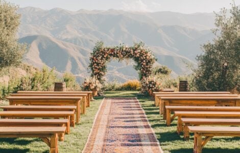 A breathtaking mountain view wedding ceremony where nature’s beauty takes center stage, enhanced by rustic benches, boho-chic decor, and stunning floral designs for an unforgettable celebration.