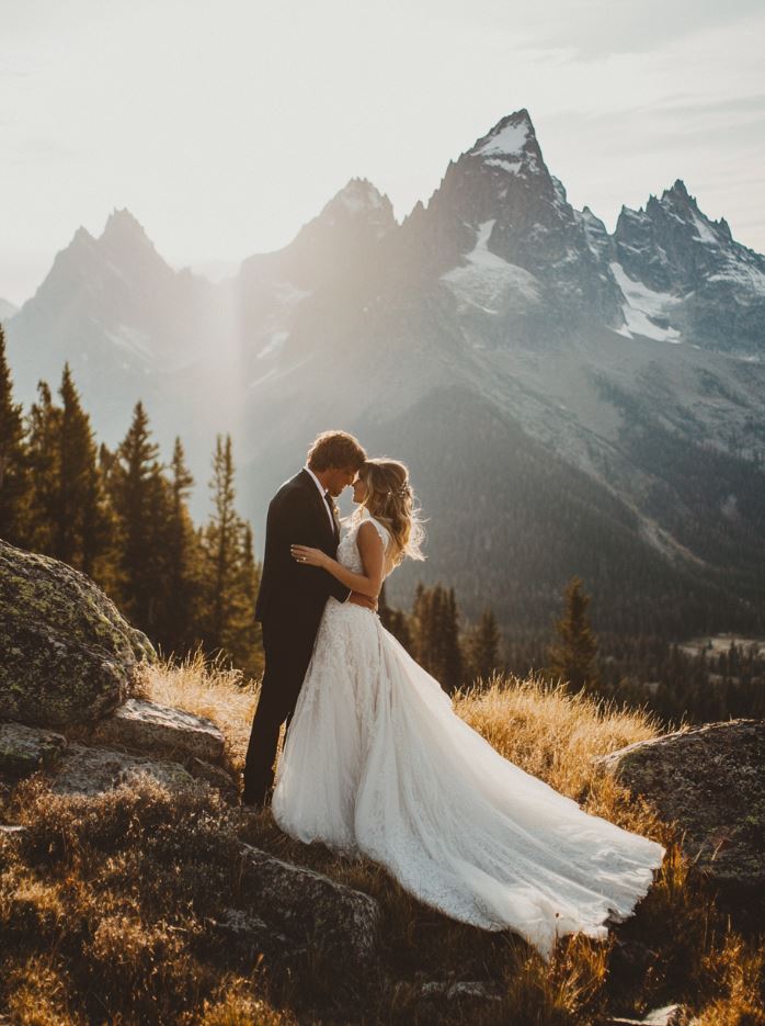 A photographer capturing a couple's wedding photos with a stunning mountain backdrop, making use of natural light and scenic mountain landscapes.