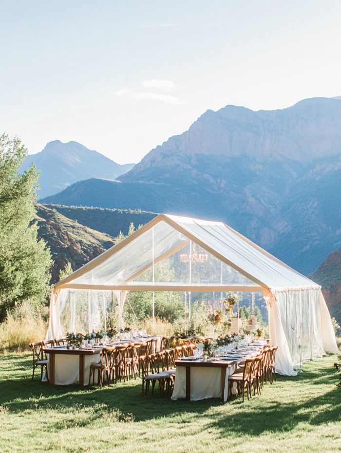 Elegant transparent reception tents set up in a mountain setting, providing shelter while offering a perfect view of the surrounding mountain landscape.