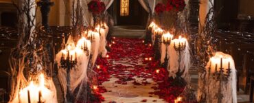 A beautifully decorated Halloween wedding aisle featuring spider web runners, vintage candelabras, and blood-red rose petals, creating an enchanting atmosphere.