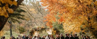 A serene outdoor wedding scene with guests celebrating together amidst autumn foliage, embodying love, gratitude, and the essence of a Thanksgiving-themed wedding.