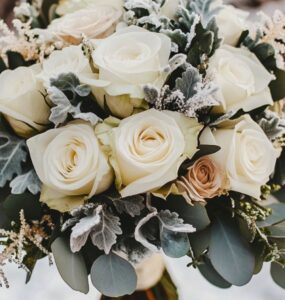 Elegant winter wedding bouquet with white roses and eucalyptus, surrounded by frosted accents, highlighting the enchanting charm of winter weddings.