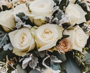 Elegant winter wedding bouquet with white roses and eucalyptus, surrounded by frosted accents, highlighting the enchanting charm of winter weddings.
