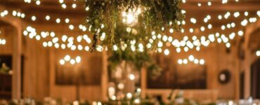 Rustic indoor wedding venue with warm string lights, wooden accents, and cozy greenery decorations, creating an elegant and intimate ambiance.
