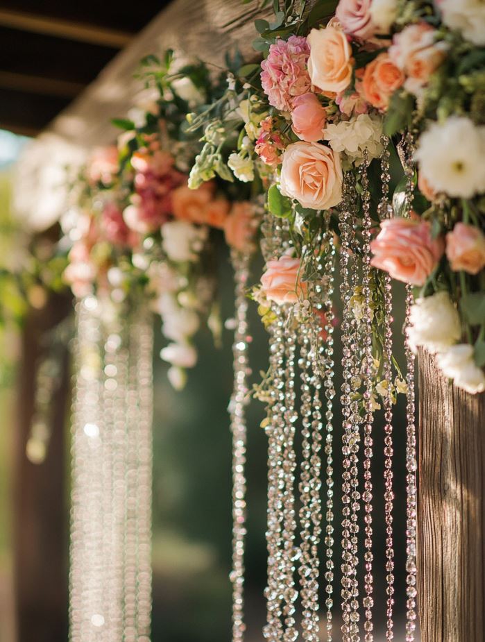 Romantic rustic wedding backdrop featuring crystal beads and fresh flowers hanging from a wooden structure for a sparkling effect.