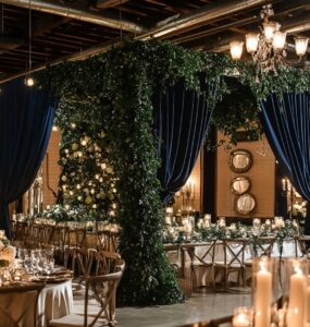 Elegant winter wedding decor featuring green and navy blue accents, including lush greenery, navy drapes, and glowing candlelight to set a timeless seasonal ambiance.