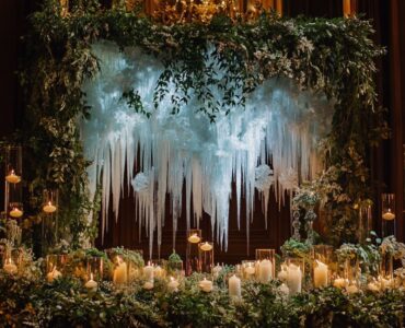 Elegant January wedding ceremony with a backdrop inspired by winter elements, featuring icy designs, cozy candlelight, and lush greenery for a warm and enchanting ambiance.