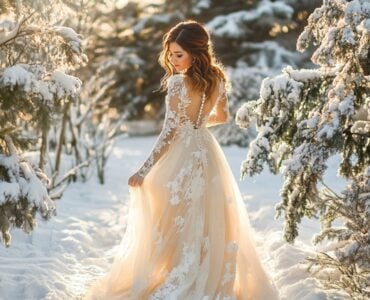 Elegant bride in a January wedding dress standing in a winter landscape, embracing the season's charm and sophistication with cozy, stylish design.