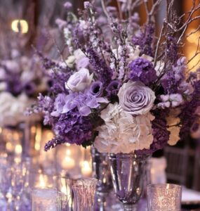 A beautifully styled winter wedding scene with purple-inspired decorations, including lavender floral arrangements, frosty silver accents, and a candlelit ambiance, highlighting the charm and elegance of purple color palettes.