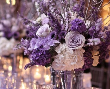 A beautifully styled winter wedding scene with purple-inspired decorations, including lavender floral arrangements, frosty silver accents, and a candlelit ambiance, highlighting the charm and elegance of purple color palettes.