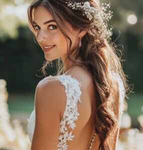 An elegant bride standing in a rustic outdoor wedding setting, her hairstyle reflecting natural beauty with soft waves and floral accents, complementing the countryside charm.