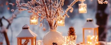 Elegant winter wedding table with centerpiece featuring snowy lanterns and fairy-lit branches, setting a warm, inviting ambiance.