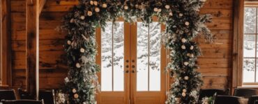 A cozy winter wedding ceremony setup featuring a flower arch decorated with winter-inspired flowers and greenery, creating a magical, seasonal backdrop for an intimate ceremony.