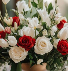 A romantic February wedding scene featuring a beautifully arranged floral centerpiece with red roses, white tulips, and soft greenery, symbolizing love and elegance.