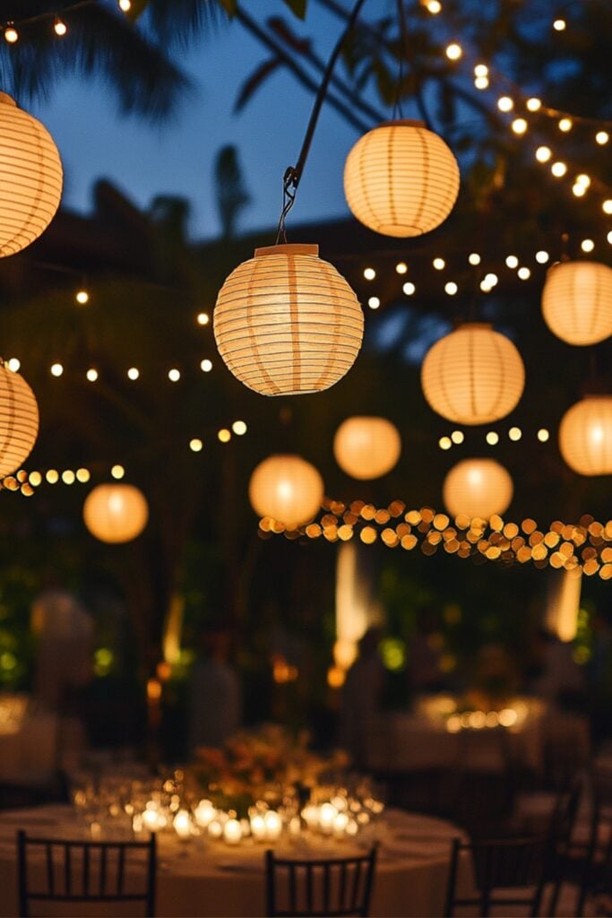 Hanging lanterns and fairy lights illuminating an outdoor wedding venue, creating a magical and romantic evening ambiance.