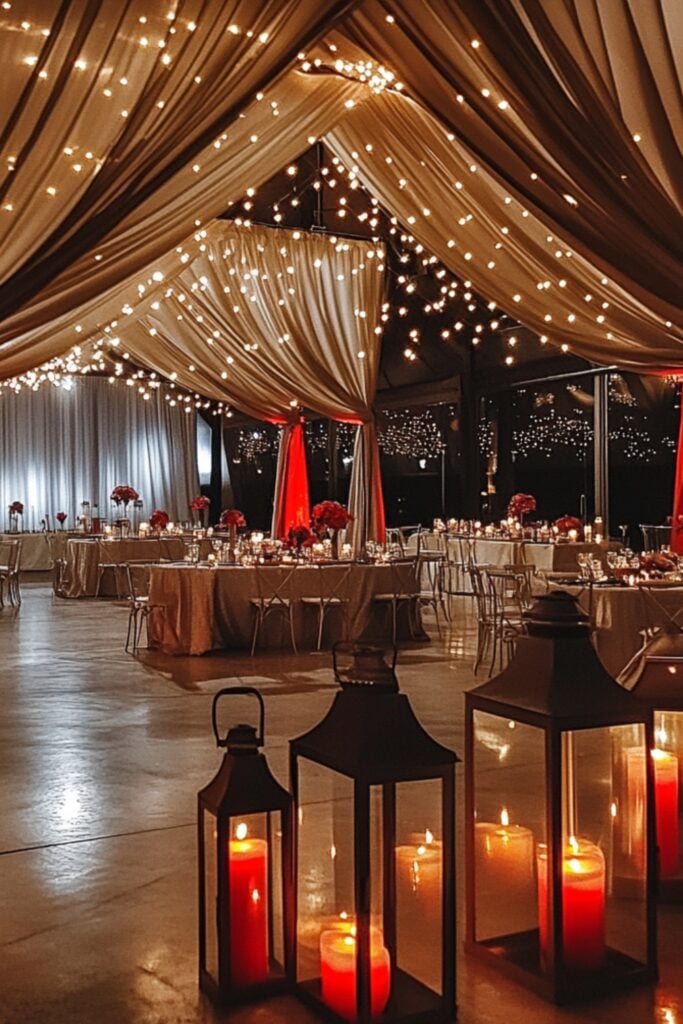 Romantic lighting with red uplights, ash grey drapes, string lights, and lanterns featuring red candles, creating a cozy and luxurious ambiance.