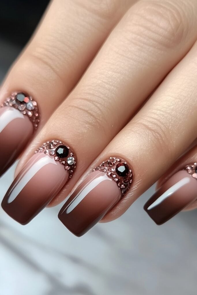 Ombre nails transitioning from blush pink to nude, with a glossy finish and small rhinestones at the tips for added elegance.
