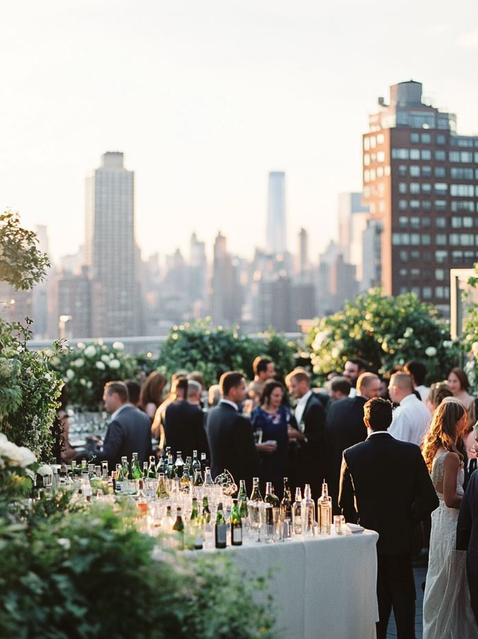 Chic rooftop garden wedding reception with lush greenery, stunning city views, and guests enjoying cocktails and appetizers in a modern, serene setting.